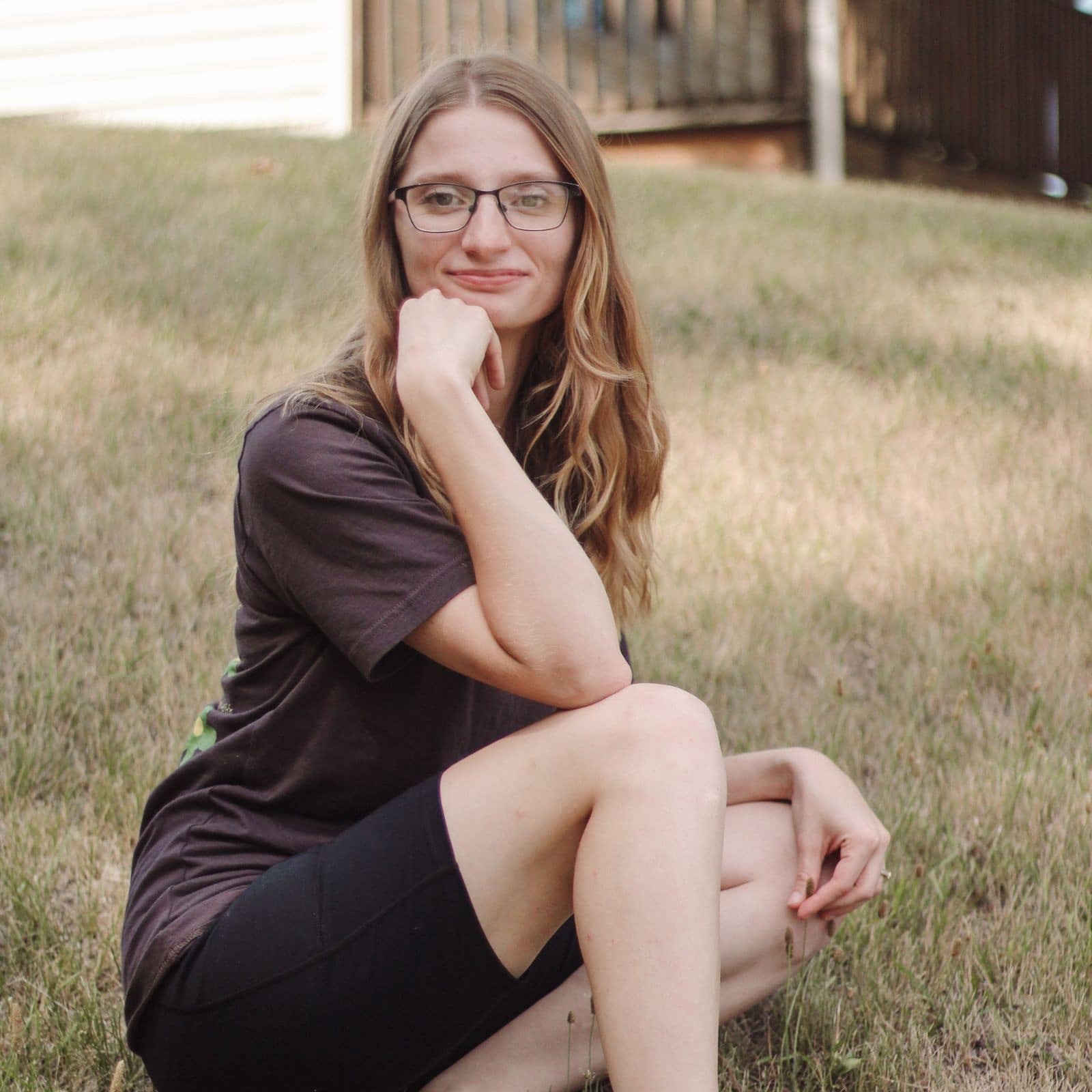 Christian Yoga Teacher Kassidy headshot sitting on a hill with hand on chin